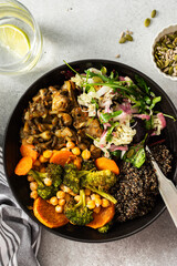 A balanced breakfast bowl with black quinoa, avocado, roast chicken, and sweet potatoes, topped with a fresh cabbage and radish salad