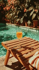 Fototapeta premium Refreshing orange drink on a wooden lounge chair by a tranquil poolside surrounded by lush greenery