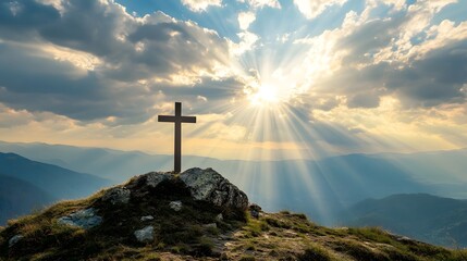 crucifix at the top of a mountain with sunlight breaking through the clouds inspirational christian image