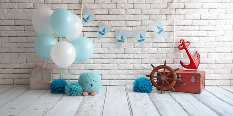 Baby shower backdrop featuring balloons, nautical decor, and a fluffy toy against a white brick wall, showcasing a festive and playful atmosphere ideal for celebrations