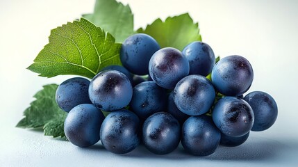 Fresh bunch of blue grapes with green leaves on light background