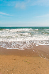 Background sea beach with waves and foam. Sandy beach and sea turquoise waves. Feeling of carelessness, enjoyment of freedom and happiness.