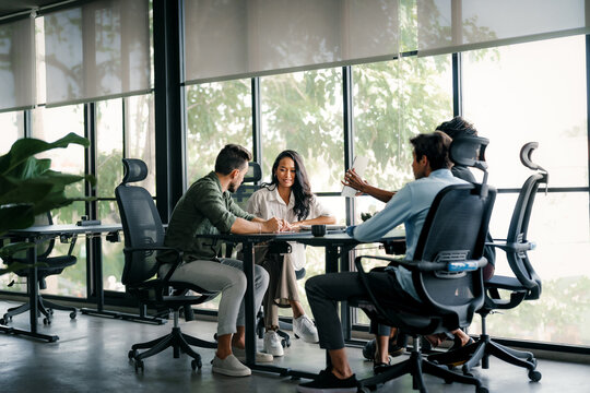 Multicultural professional businesspeople working together on research plan in boardroom.