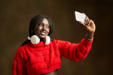 Young woman taking selfie with smartphone and headphones