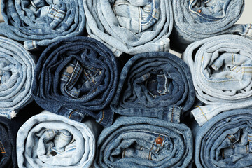 Different stylish rolled jeans as background, top view