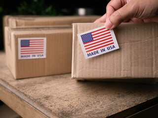 Man Hands applying MADE IN USA flag label on a shipping cardboard box.