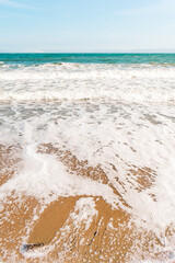 Background sea beach with waves and foam. Sandy beach and sea turquoise waves. Feeling of carelessness, enjoyment of freedom and happiness.