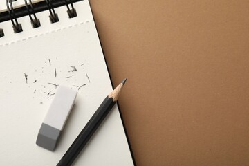 Eraser, pencil, scraps and notebook on brown background, top view. Space for text