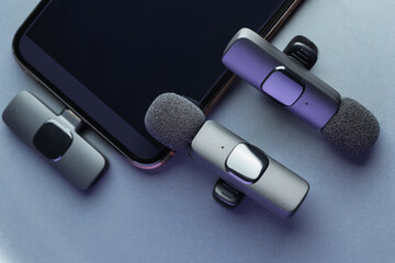 Lavalier microphones and smartphone on light grey background, flat lay