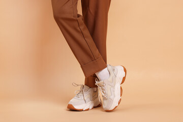Woman wearing stylish sneakers on beige background, closeup