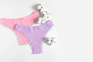 Women's underwear. Beautiful panties and cotton flowers on white background, flat lay. Space for...