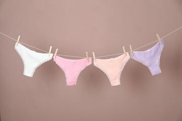 Women's underwear. Beautiful panties on clothes line against light brown background