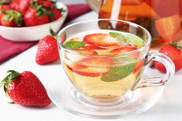 Aromatic fruit tea, strawberries and mint on white table, closeup