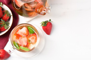 Aromatic fruit tea with strawberries and mint on white marble table, flat lay. Space for text
