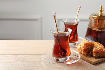 Tasty Turkish tea served with baklava on wooden table. Space for text