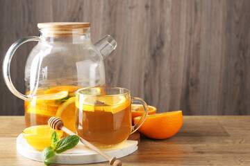 Aromatic fruit tea with orange, lemon, honey and mint on wooden table, space for text