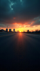 Obraz premium A breathtaking sunset casting a warm glow over an urban cityscape, captured from a perspective of a long road