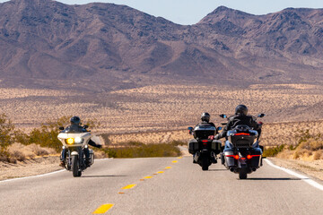 Passing motorcyclists wave at each other on lonely desolate desert road isolated remote two lane highway biker bikers motorcycle motorbike
