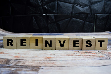 Concept word Reinvest on wooden blocks on a wooden table