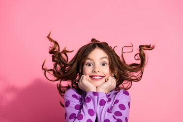 Excited Young Girl with Flipping Hair Posing Against a Pink Background in Trendy Apparel Showcasing...