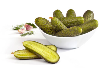 Ogórki małosolne w białej miseczce z czosnkiem i liściem laurowym na białym tle