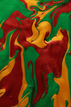 Swirling red, green, and yellow metallic paint background