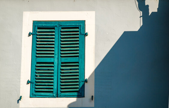 Picturesque turquoise window shutters on a sunny day