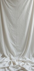 Obraz premium A pristine white sheet of soft, smooth fabric drapes elegantly across a wooden table, catching the light and casting gentle shadows, creating a serene and minimalist atmosphere.