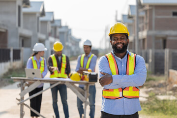 A group of construction workers engages in planning at a housing development with lead worker...