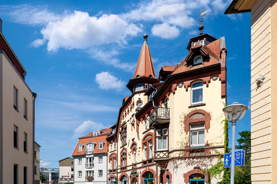 Historic residential buildings with ornate towers and red rooftops in the old town of Gotha, Thuringia under a bright blue sky