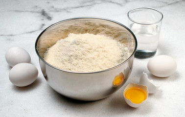 mesa de mármore com tigela com farinha de trigo, ovos e água