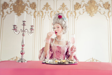 A young woman dressed in elaborate vintage attire, enjoying a luxurious meal in a baroque-inspired...