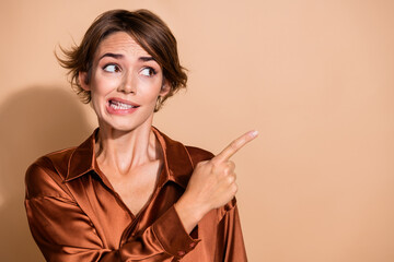 Photo of doubtful unsure lady dressed silky shirt showing finger empty space isolated beige color...