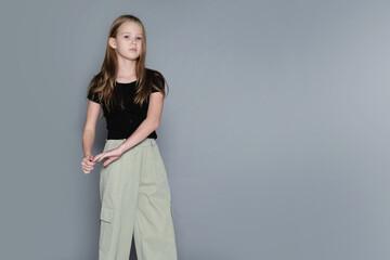 A calm girl stands confidently in a simple studio setting, looking thoughtfully ahead. Authentic...