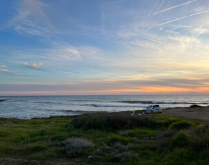 Cyprus Island. Sunset over the sea. Car standing on the beach at sunset.