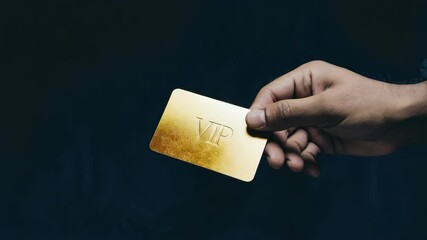 Close-up of a hand holding a golden VIP card against a dark background symbolizing exclusivity, luxury, and high society membership.