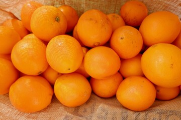 A vibrant display of fresh oranges fills a woven basket, showcasing their bright orange colour