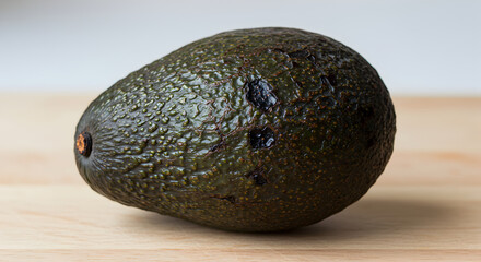 Unripe Avocado Pear With Blemishes Set Against A Wooden Surface Still Life