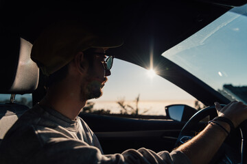 Young caucasian man driving a car at sunset in Tenerife, Canary Islands