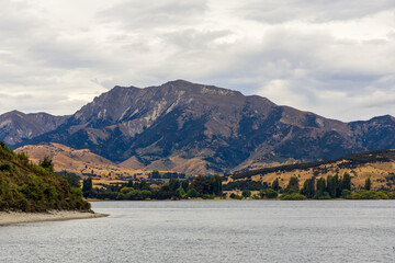 Lake Wanaka, a summer cloudy afternoon with a mountain range and the town of Wanaka on the shore....