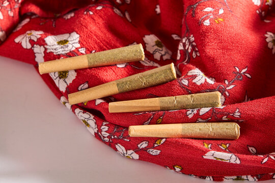 Pre-Rolled Herbal Cones Arranged on Red Floral Fabric