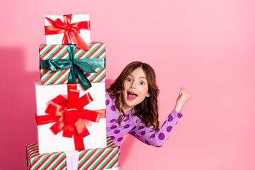 Excited Young Girl Celebrates with a Stack of Holiday Presents in a Cheerful and Festive Setting Featuring a Vibrant Pink Background