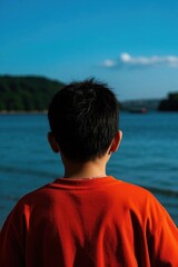 Fototapeta premium there is a young boy standing on the beach looking out at the water