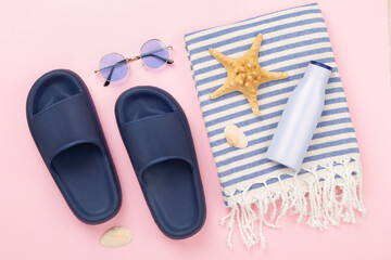 Beach towel with summer accessories on color background, top view