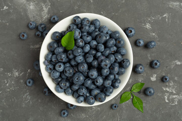 Bowl with fresh bright blueberries on concrete background,top view