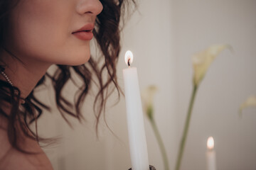 Romantic close-up of a woman’s face, candle flame and soft floral background