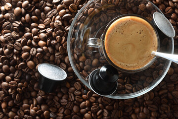 Espresso cup on ground coffee with capsules around top view