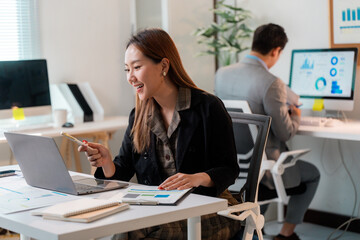 Asian businesswoman having video call and pointing at laptop screen during online meeting in office