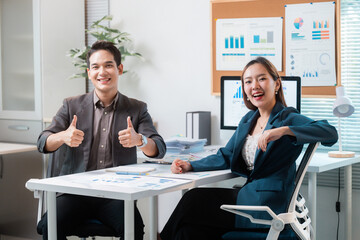 Asian businesspeople showing thumbs up while working together in office