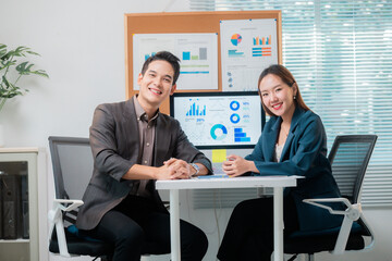 Asian business partners smiling and working together analyzing charts in the office